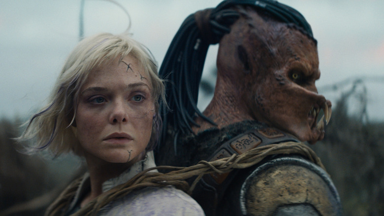 Elle Fanning as Thia stands back-to-back with Dimitrius Schuster-Koloamatangi as Dek in Predator: Badlands