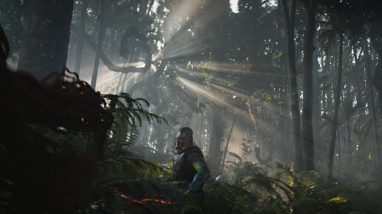 Dimitrius Schuster-Koloamatangi as Dek wanders through a rainforest-like environment in Predator: Badlands