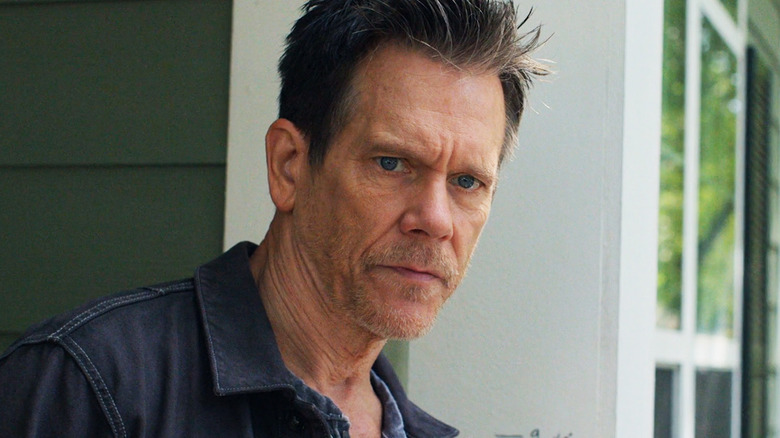 Kevin Bacon as Hub Halloran standing in a doorway outside in The Bondsman