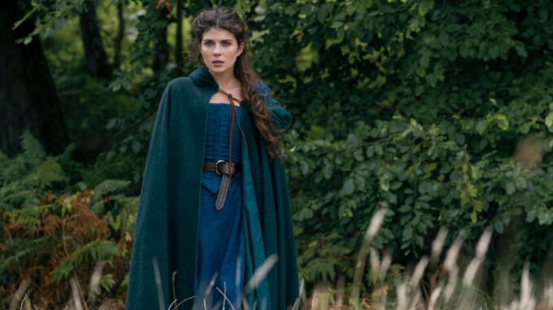 Emily Bader as Jane, wearing a cloak and standing in a forest clearing in My Lady Jane