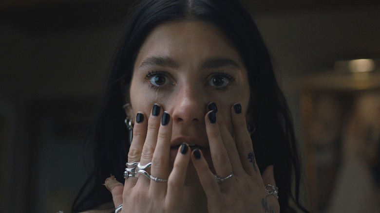 Camila Morrone's Rachel cries while touching her face in Something Very Bad Is Going to Happen