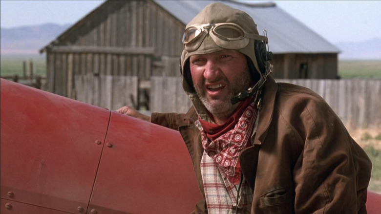 Randy Quaid as Russell Casse in front of his crop plane and a shed in Independence Day