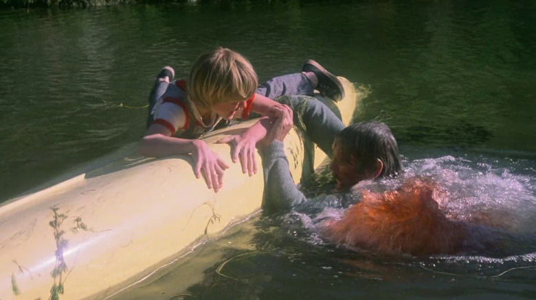 A man being eaten by Piranhas as a young boy seeks refuge on top of a kayak in Piranha