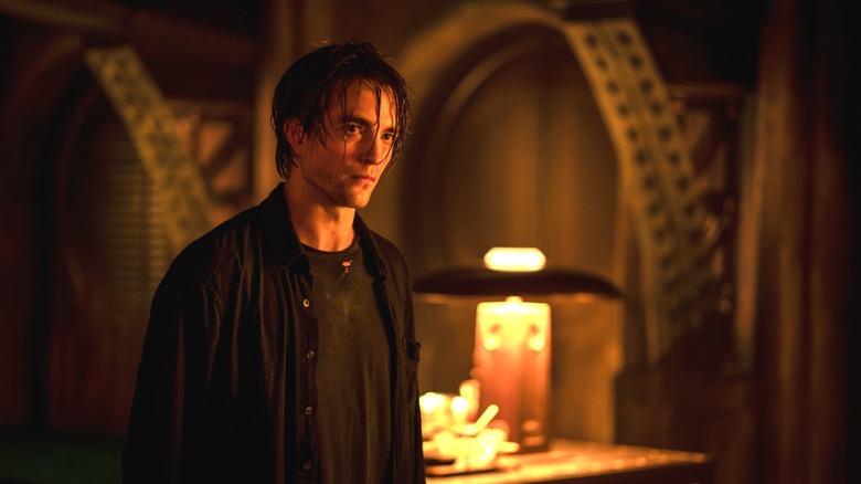 Robert Pattinson as Bruce Wayne standing in the Batcave with wet hair in The Batman