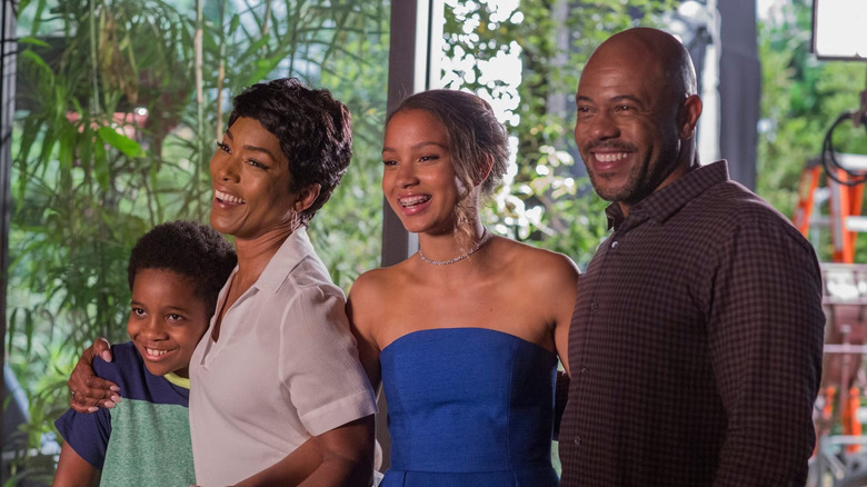 Michael Grant (Rockmond Dunbar) and family stand together in a house, smiling and looking to their right on 9-1-1