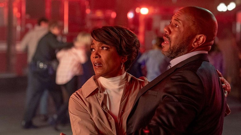 Athena and Michael Grant stand next to each other outside and look up in anguish at a building