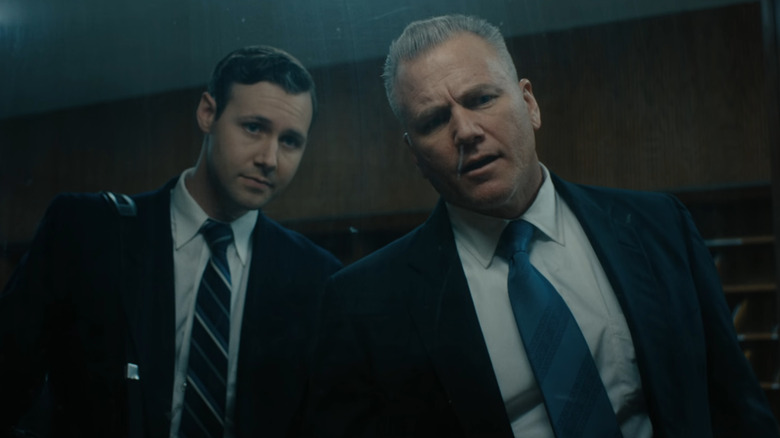 Sean Carrigan sebagai John Douglas dan Caleb Ruminer sebagai Robert Ressler melihat melalui cermin satu arah di Monster: The Ed Gein Story