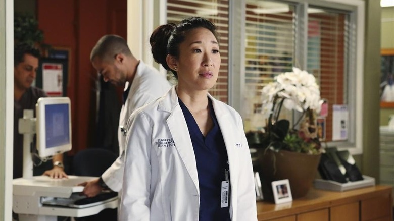 Cristina with her hair tied up looking at something in the distance on Grey's Anatomy