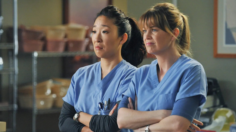 Cristina and Meredith standing together looking dismayed on Grey's Anatomy