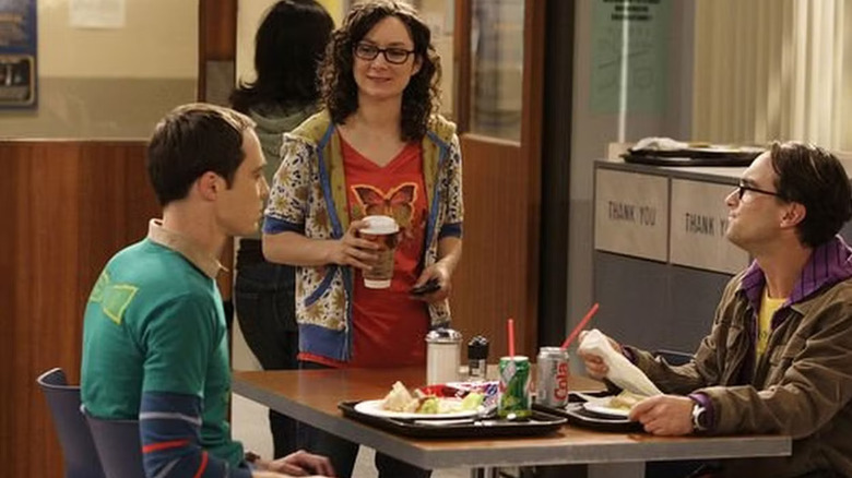 Leslie in the cafeteria standing over Leonard and Sheldon's table on The Big Bang Theory