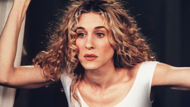 Carrie looking out of her window in a white tank top on Sex and the City