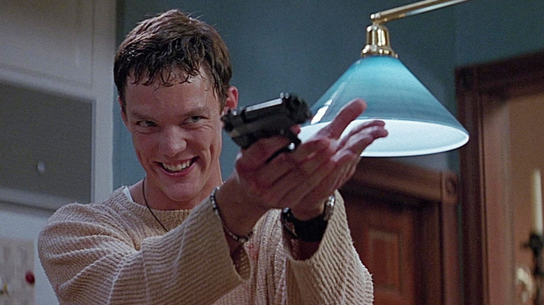 Stu holding a gun and smiling in Sidney's kitchen in Scream