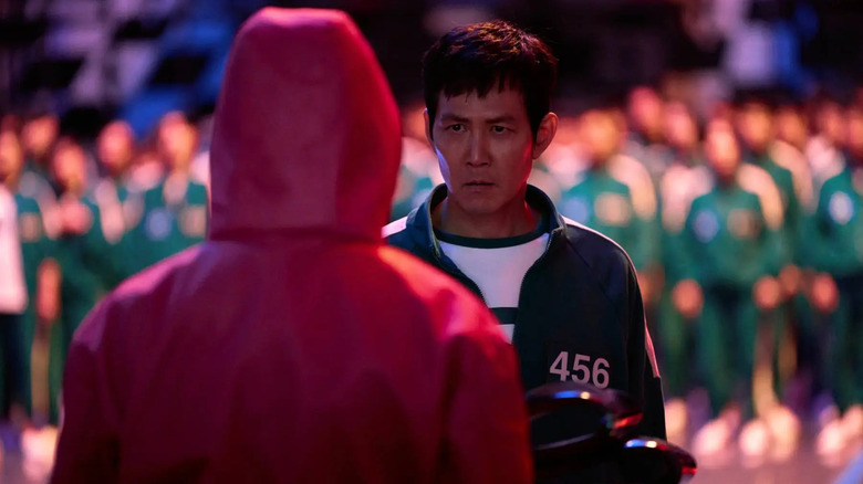 Gi-hun faces off with a masked guard in Squid Game