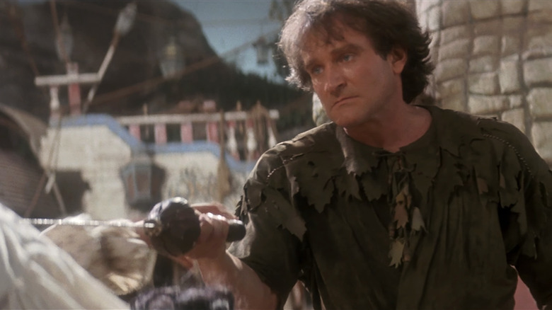 Robin Williams as Peter Banning holds a sword up in Hook