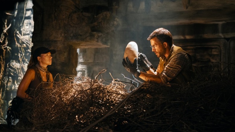 Zora looks at Loomis grabbing a dinosaur egg and staring in awe in Jurassic World Rebirth