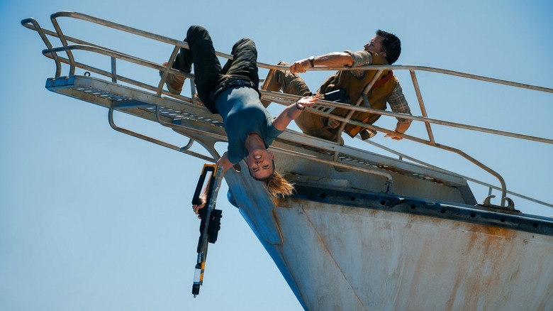 Zora holds on to dear life as she hangs from a boat's rail in Jurassic Wold Rebirth