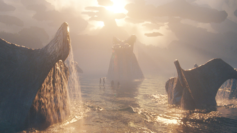 Several whalelike Tulkun breaching the water and surrounding a few tiny figures in Avatar: Fire & Ash