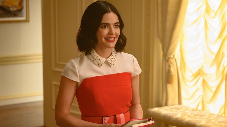 Lucy Hale as Katy smiling while holding a notebook in Katy Keene
