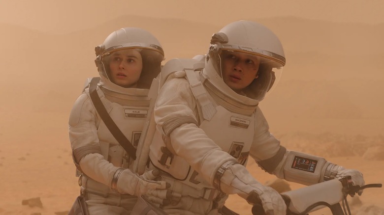 Sean Kaufman as Alex Poletov and Ruby Cruz as Lily Dale wearing spacesuits and riding on a motorcycle on Mars in For All Mankind