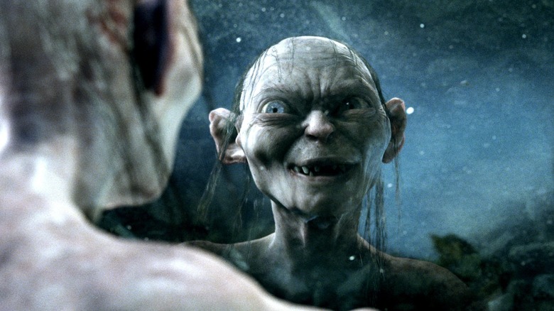 Andy Serkis as Gollum looking and smiling at a reflection of himself in a pool of water in The Lord of the Rings: The Return of the King
