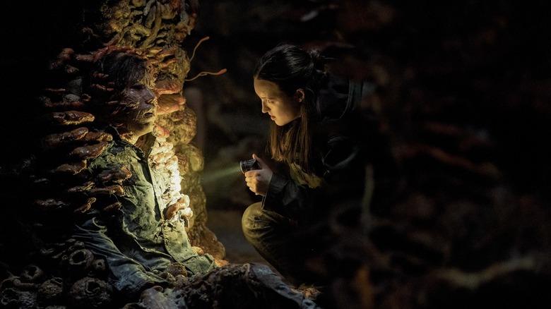 Ellie looking at spore zombies with a flashlight in The Last of Us