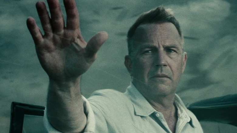 Kevin Costner's Jonathan Kent holds his hand up amid a tornado in Man of Steel