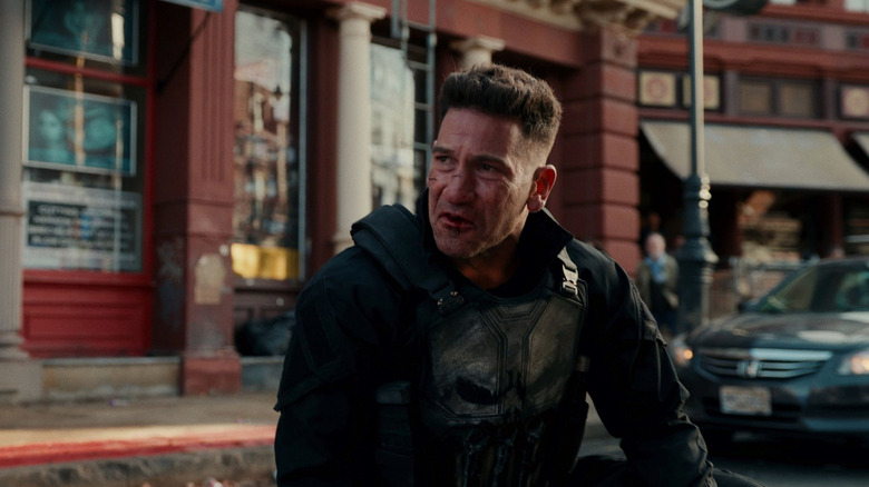 Jon Bernthal as Frank Castle wearing his Punisher outfit and kneeling in a busy street in Spider-Man: Brand New Day