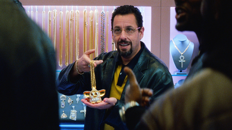 Howard holding up a gem-encrusted Furby in Uncut Gems