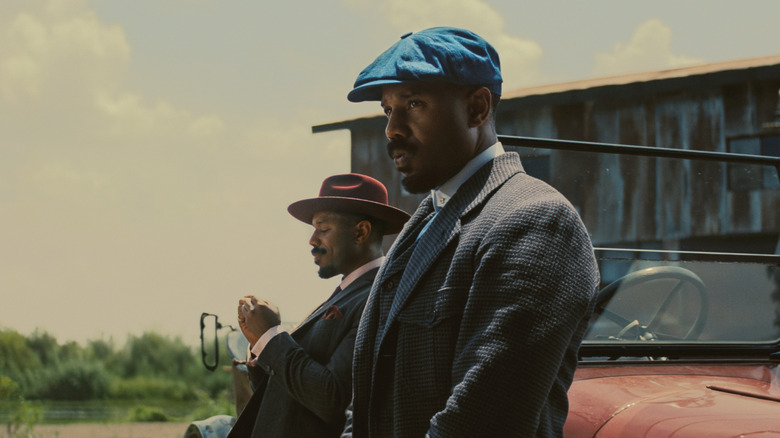 Michael B Jordan as Smoke and Stack leaning up against their car in Sinners
