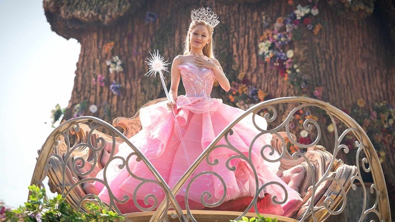 Glinda com a mão no coração olhando para Munchkins em Wicked: Part One