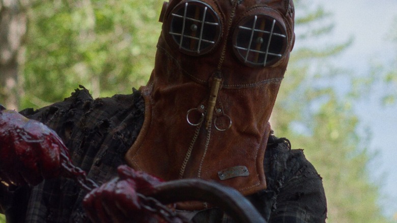 Johnny (Ry Barrett), masked, grabs a chain and a hook in the film In a Violent Nature (2024)