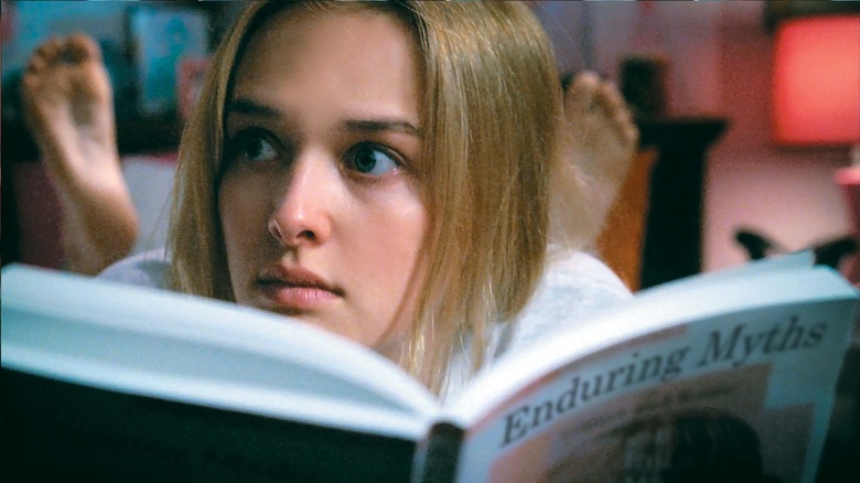 Dawn (Jess Weixler) overhears sound through her bedroom walls while reading a book in bed in Teeth (2007)