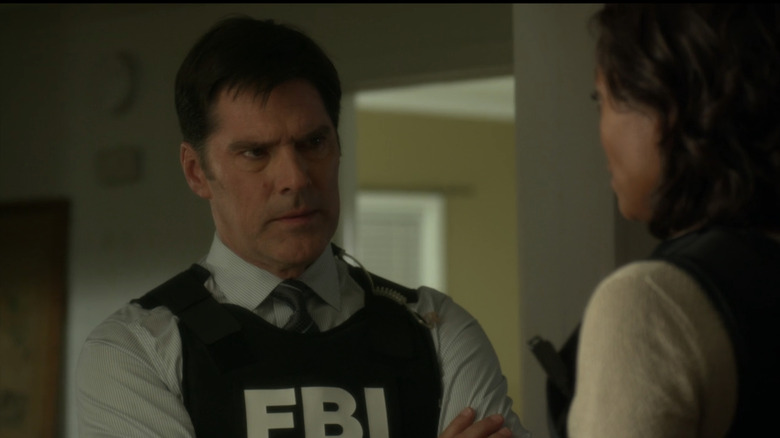 Thomas Gibson's Aaron Hotchner stands in an office wearing an FBI vest in Criminal Minds