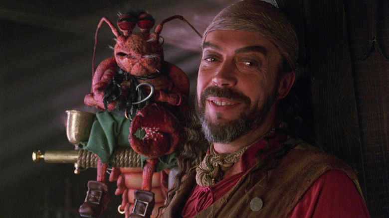 Tim Curry as Long John Silver smiling with his lobster Polly in Muppet Treasure Island