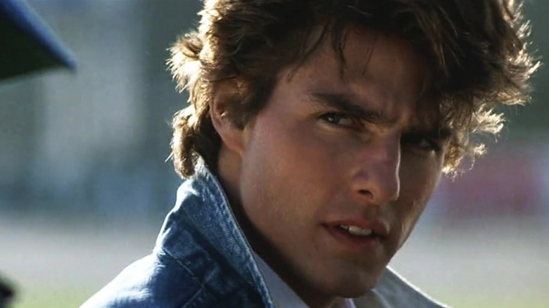 Tom Cruise as Cole Trickle wearing a jean jacket and giving a piercing look in Days of Thunder