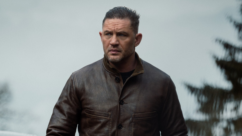 Tom Hardy as Harry Da Souza wearing a leather jacket and walking away from a car in MobLand