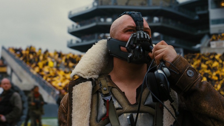 Tom Hardy's Bane speaks into a headset microphone in The Dark Knight Rises