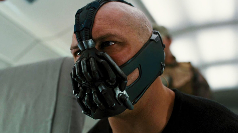 Tom Hardy's Bane looks intense as he kneels down on a plane in The Dark Knight Rises