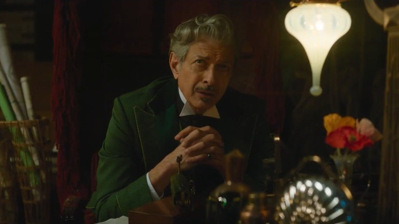 Jeff Goldblum as the Wizard of Oz sitting with his hands folded together in Wicked: For Good