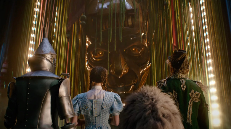 The Tin Man, Dorothy, Cowardly Lion, and Scarecrow looking up at the Wizard of Oz in Wicked: For Good
