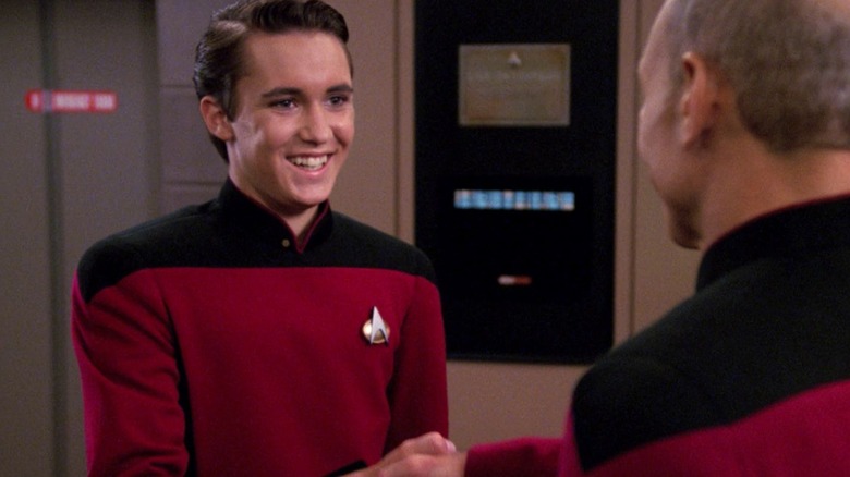 Wesley Crusher, on the business deck, smiling and shaking the hand of Captain Picard.