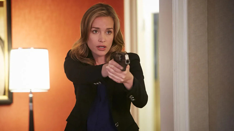 Annie pointing a gun in a hotel room in Covert Affairs