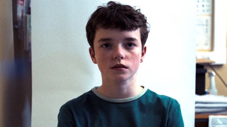 Owen Cooper as Jamie Miller standing against a white wall in Adolescence