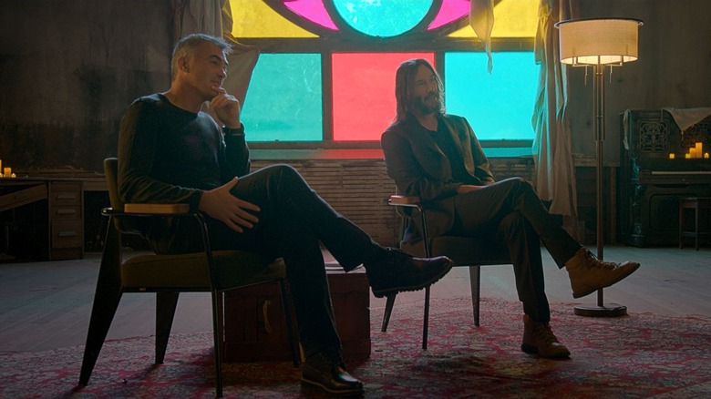 Chad Stahelski sits next to Keanu Reeves on the set of Wick is Pain