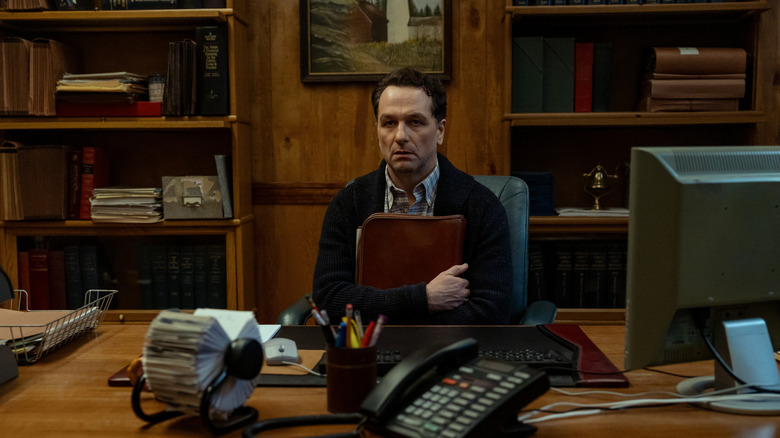 Tom sits at his desk, stunned, in Widow's Bay