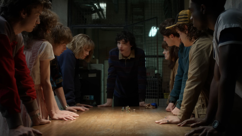 Finn Wolfard as Mike Wheeler and his allies gathered around a table in Stranger Things season 5