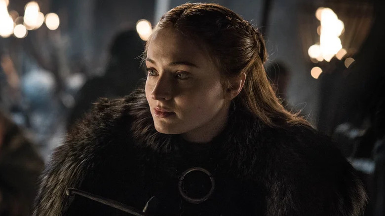Sansa Stark (Sophie Turner) stands outside surrounded by men with torches in Game of Thrones