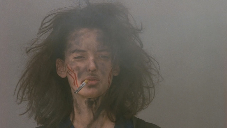 Veronica (Winona Ryder) fuma un cigarrillo con tierra y sangre en la cara en Heathers