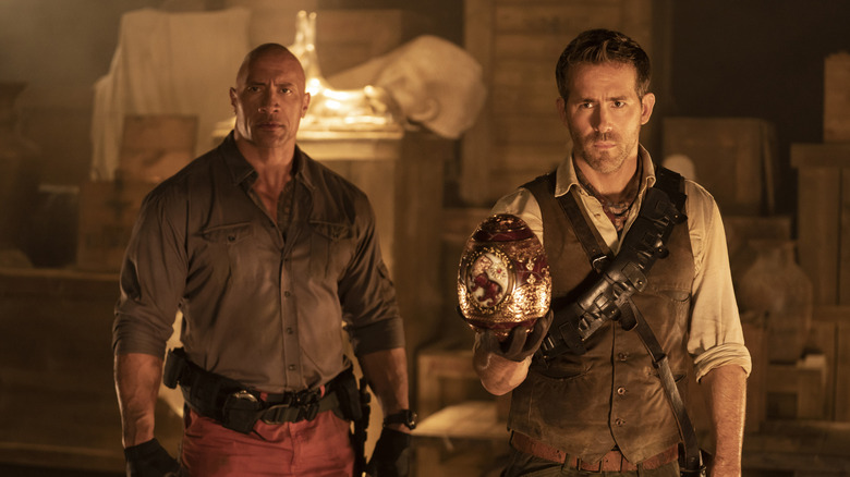Nolan holding a gilded egg next to John in Red Note