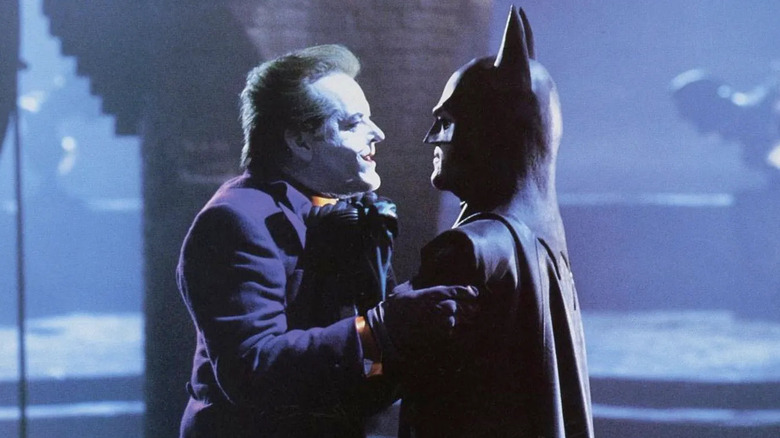 Batman (Michael Keaton) carries Joker (Jack Nicholson) by his authorship in Batman (1989)